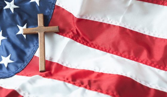 A cross rests on an American flag in this stock image.