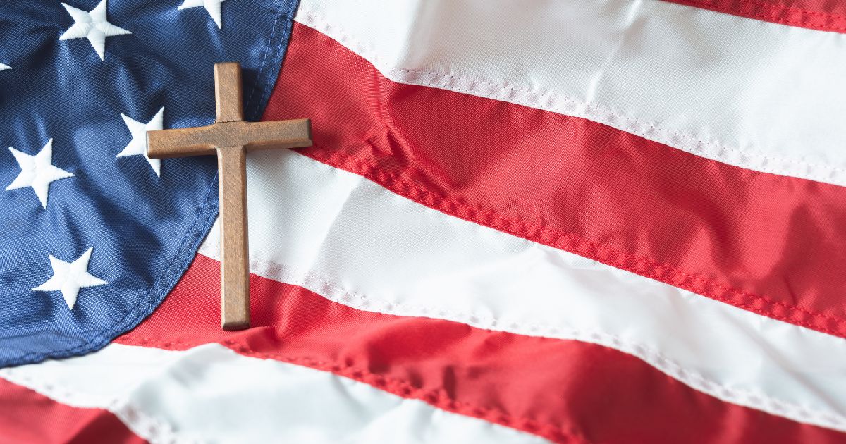 A cross rests on an American flag in this stock image.