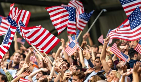 A crowd waves American flags in this stock image.