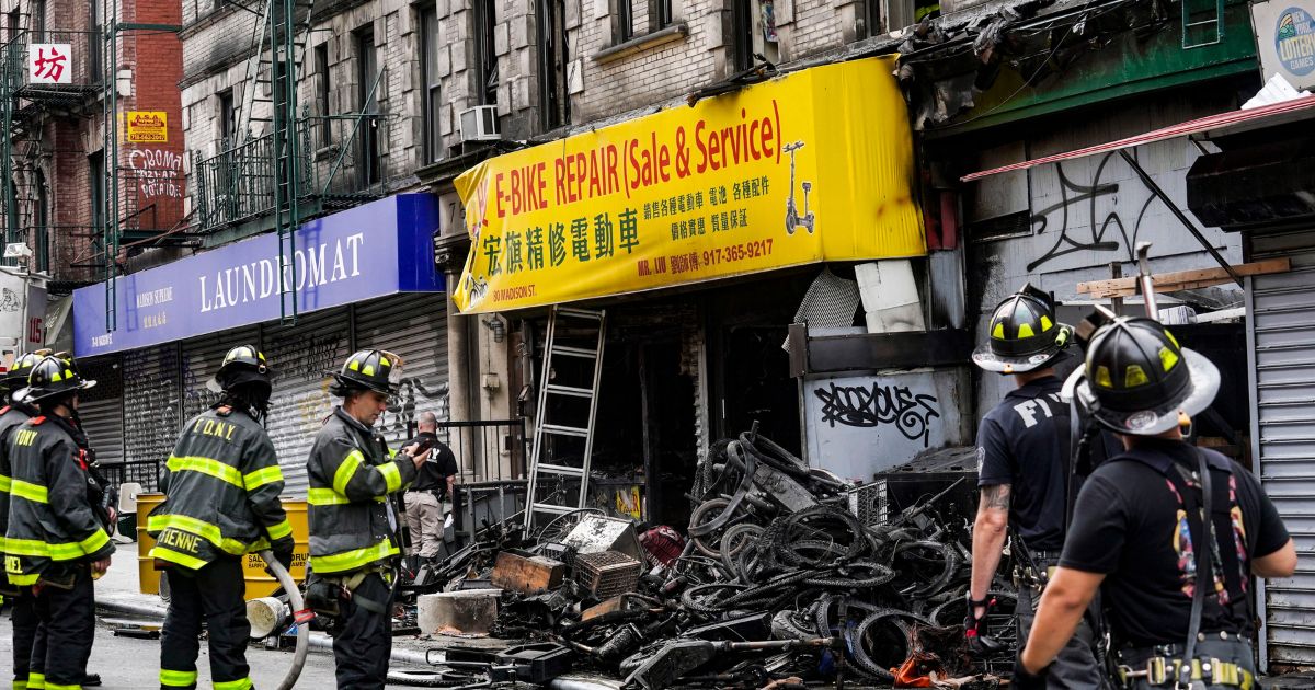 Firefighters and investigators go through the aftermath of a fire which authorities say started at an e-bike shop and spread to upper-floor apartments on Tuesday in New York.