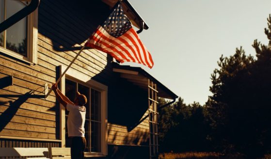 A man raises the American flag in this stock image.