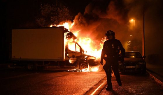 A French anti riot police officer walk past a burning truck in Nantes, western France on early July 1, 2023, four days after a 17-year-old man was killed by police in Nanterre, a western suburb of Paris.
