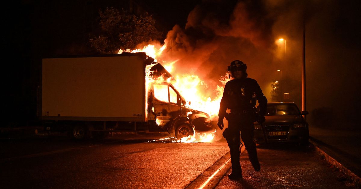 A French anti riot police officer walk past a burning truck in Nantes, western France on early July 1, 2023, four days after a 17-year-old man was killed by police in Nanterre, a western suburb of Paris.