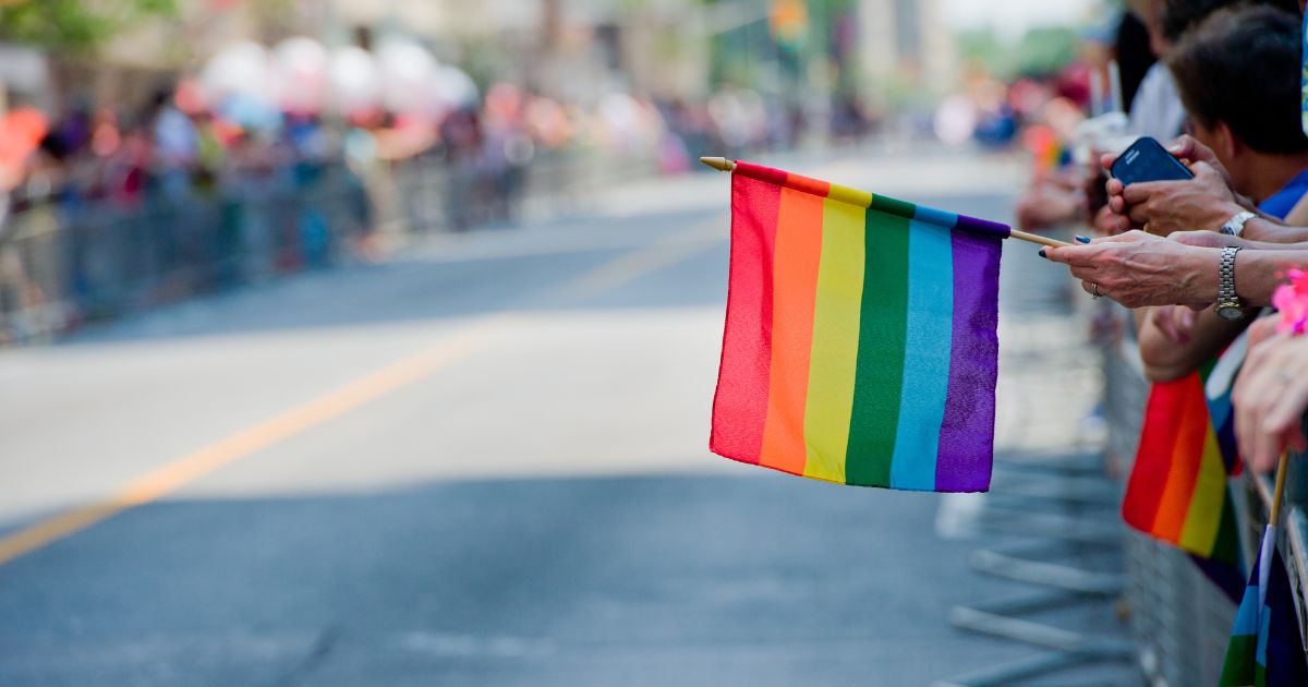 A woman holds a rainbow flag in this stock image.