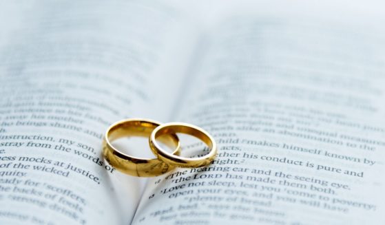 Wedding bands rest on an open Bible in this stock image.