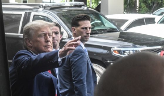 Former President Donald Trump waves to supporters while heading into Versailles, a popular Cuban restaurant in Miami, after his arraignment Tuesday on federal charges.