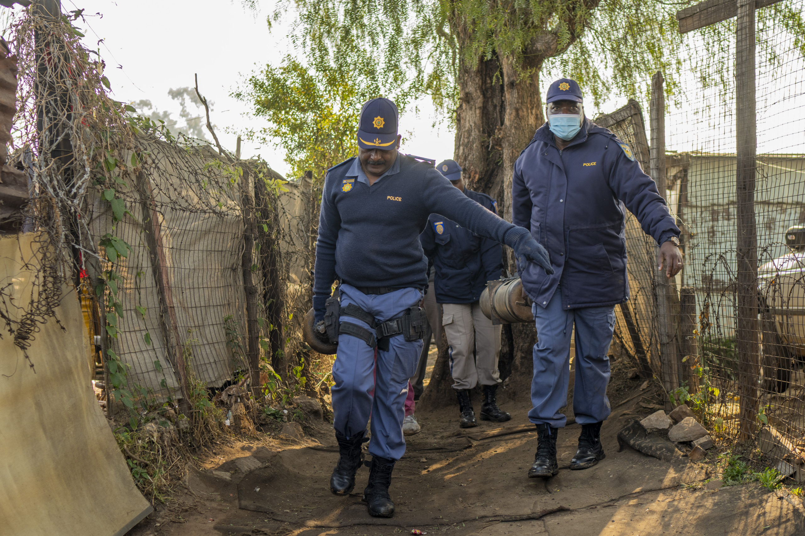 South African police officers remove gas cylinders used by illegal gold miners in the Angelo Informal Settlement in Boksburg, South Africa, Thursday. South African police said at least 17 people, including three children, have died from a leak of a toxic nitrate gas that was being used by illegal miners to process gold.