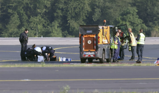 Police officers and security personnel stand on the airfield in Dusseldorf, Germany, on Thursday and try to detach activists of the group Last Generation who glued themselves to the asphalt.