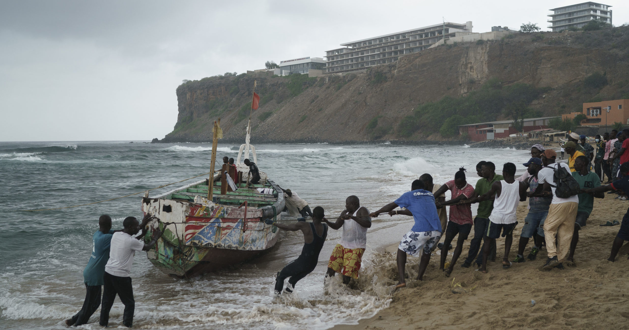 People work together to pull the capsized boat ashore at the beach where several people were found dead in Dakar, Senegal, on Monday.