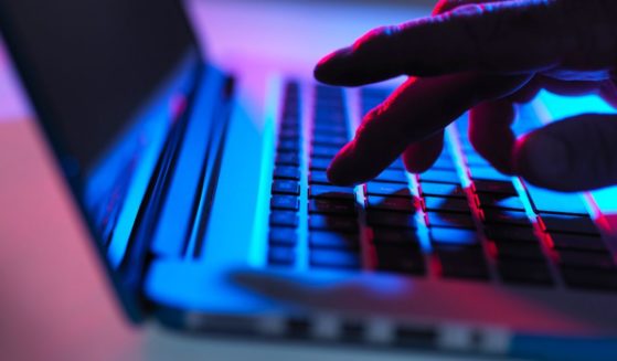 This stock photo depicts a computer hacker typing on a keyboard.