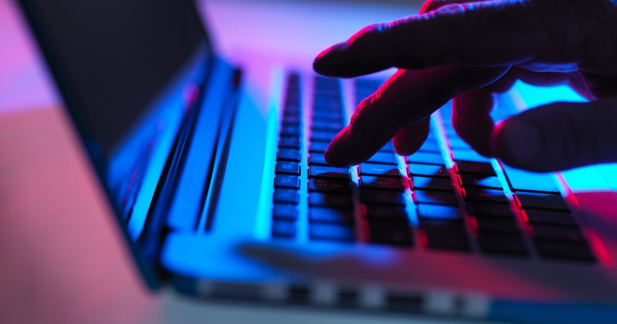 This stock photo depicts a computer hacker typing on a keyboard.