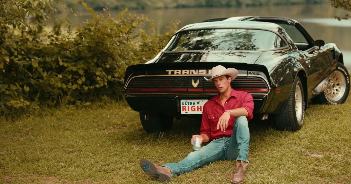 Seth Weathers, aka "Conservative Dad," sits next to a Trans Am in a promo video for Ultra Right Beer.