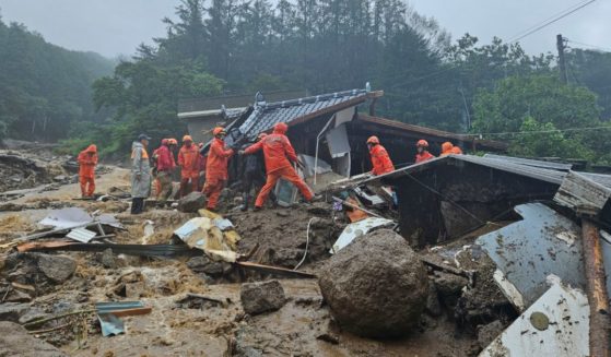 Rescue workers search for people in a house that collapsed in a landslide caused by heavy rain in Yeongju, South Korea, on Saturday.