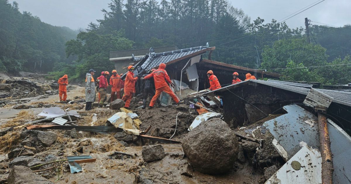 Rescue workers search for people in a house that collapsed in a landslide caused by heavy rain in Yeongju, South Korea, on Saturday.