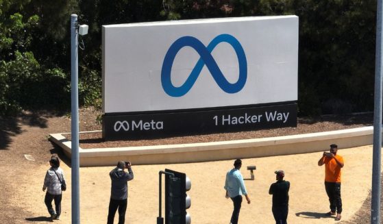 In an aerial view, people gather in front of a sign posted at Meta headquarters in Menlo Park, California, on Friday.