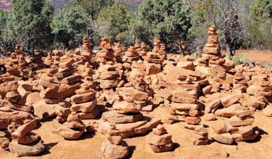 A large group of rock cairns is located at the end of a hiking trail.