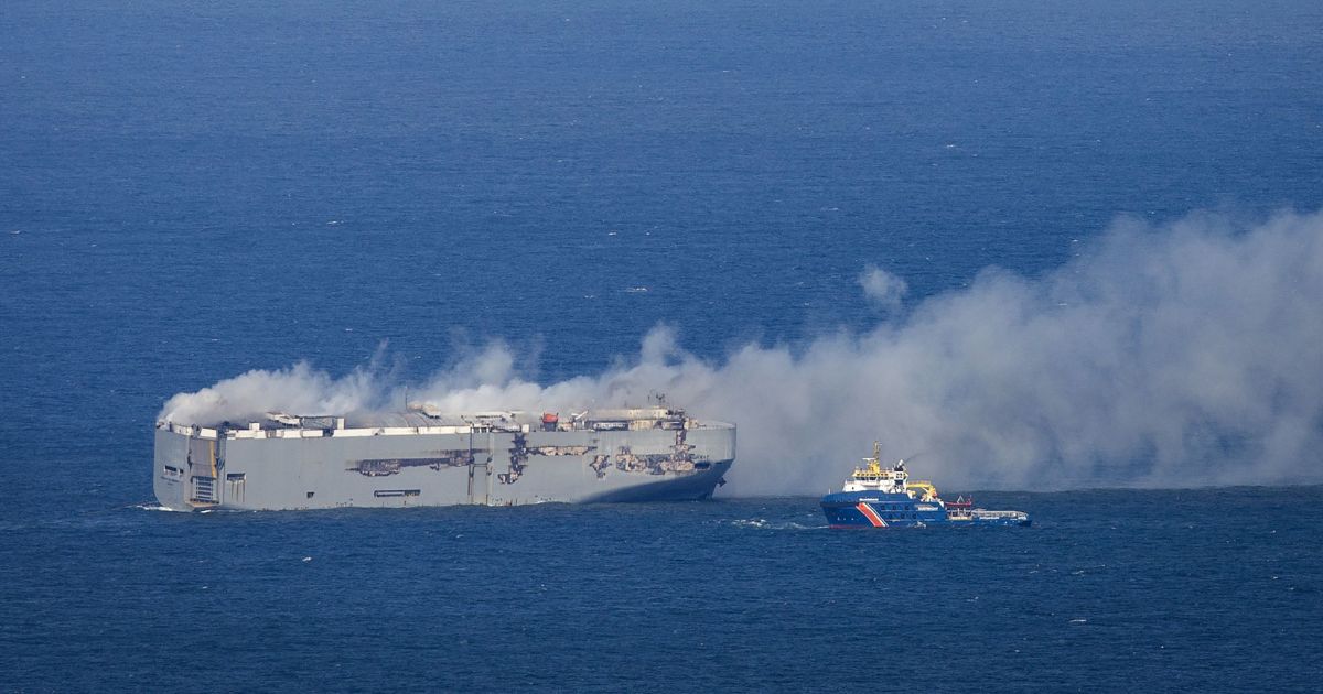 A Dutch coast guard boat approaches the Panamanian-registered car carrier cargo ship Fremantle Highway on fire off the coast of the northern Dutch island of Ameland on Wednesday.