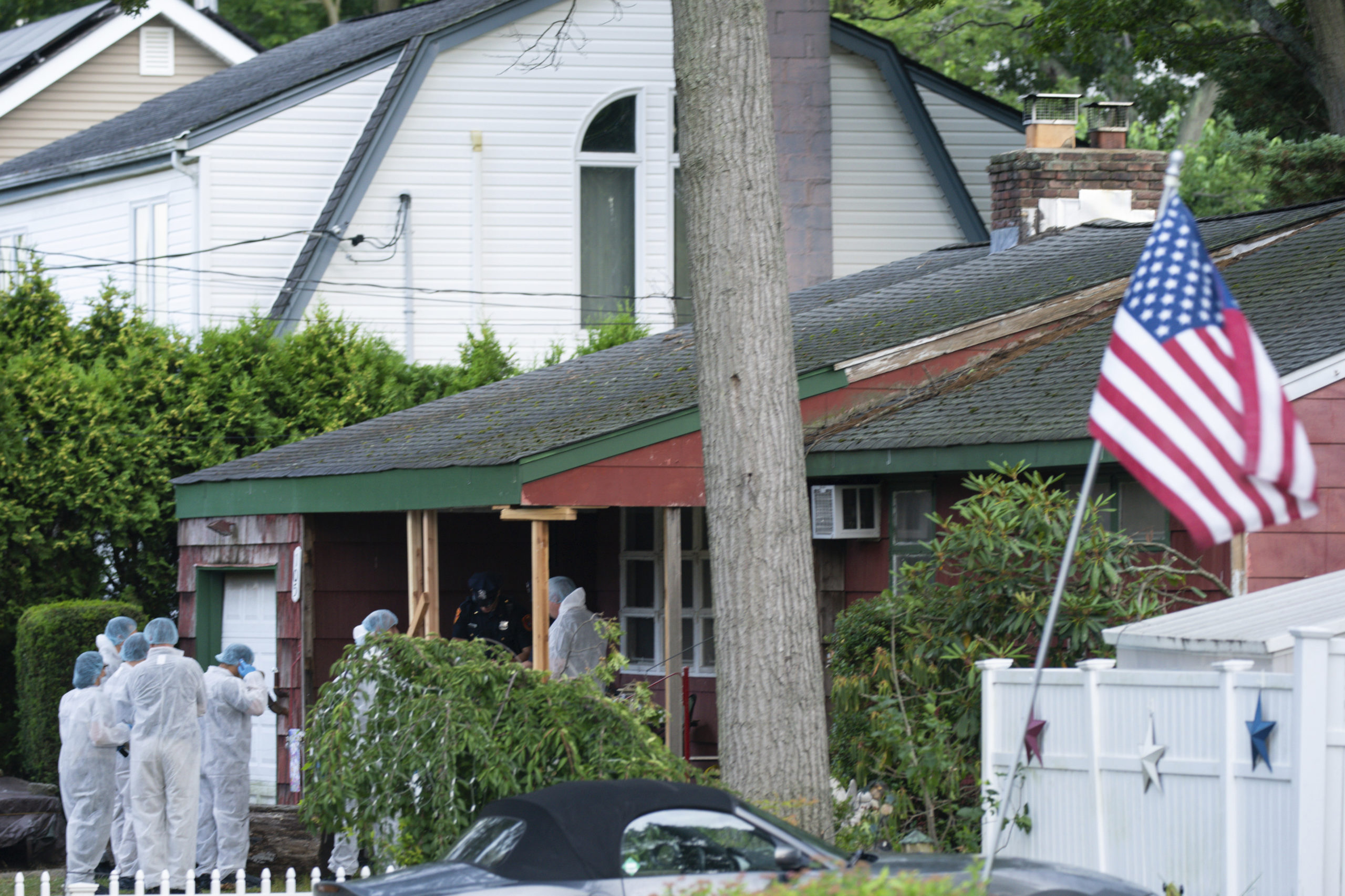 Crime laboratory officers arrive Friday at the house where a suspect was taken into custody on New York's Long Island in connection with a long-unsolved string of killings known as the Gilgo Beach murders.