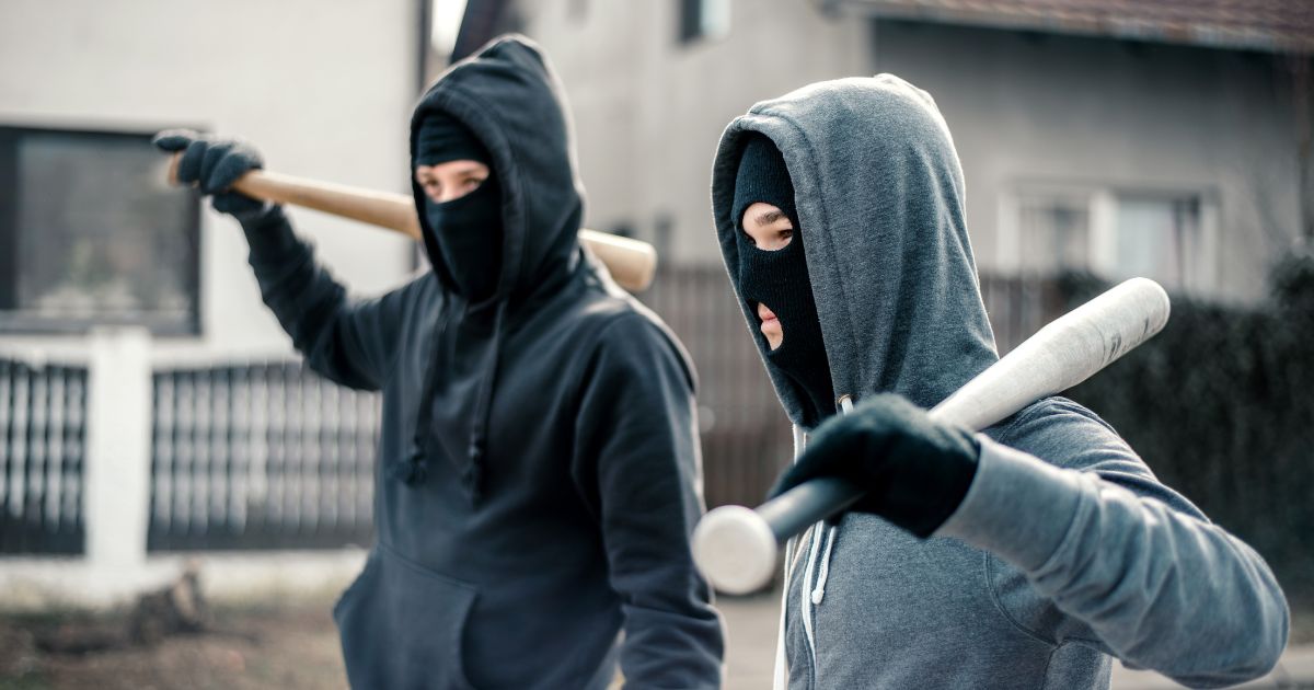 This stock image shows young men wearing masks and carrying baseball bats.
