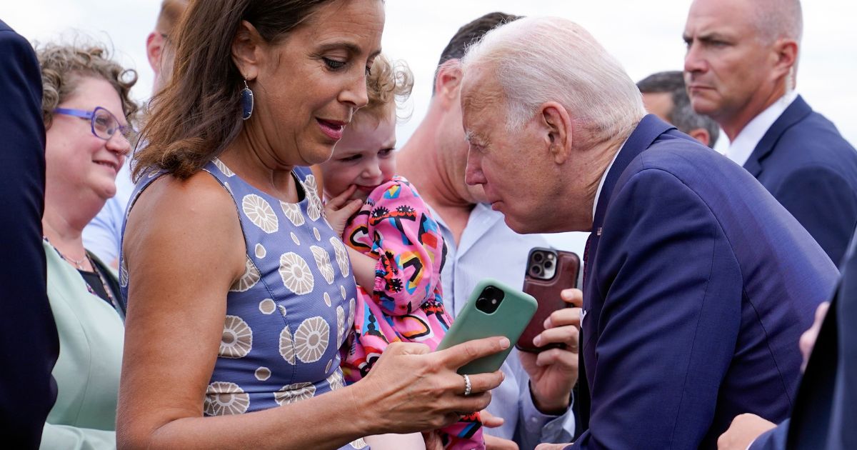 President Joe Biden talks to a child as he greets embassy staff members and their families before boarding Air Force One at Helsinki-Vantaan International Airport in Helsinki, Finland, Thursday.