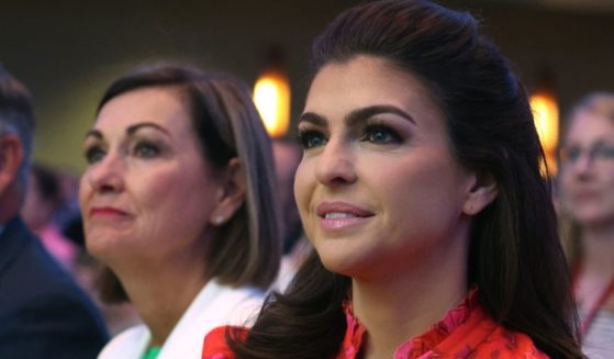 Iowa Governor Kim Reynolds (L) and Casey DeSantis, the wife of Florida Governor Ron DeSantis, listen as Ron DeSantis speaks at the Family Leadership Summit on Friday in Des Moines, Iowa.