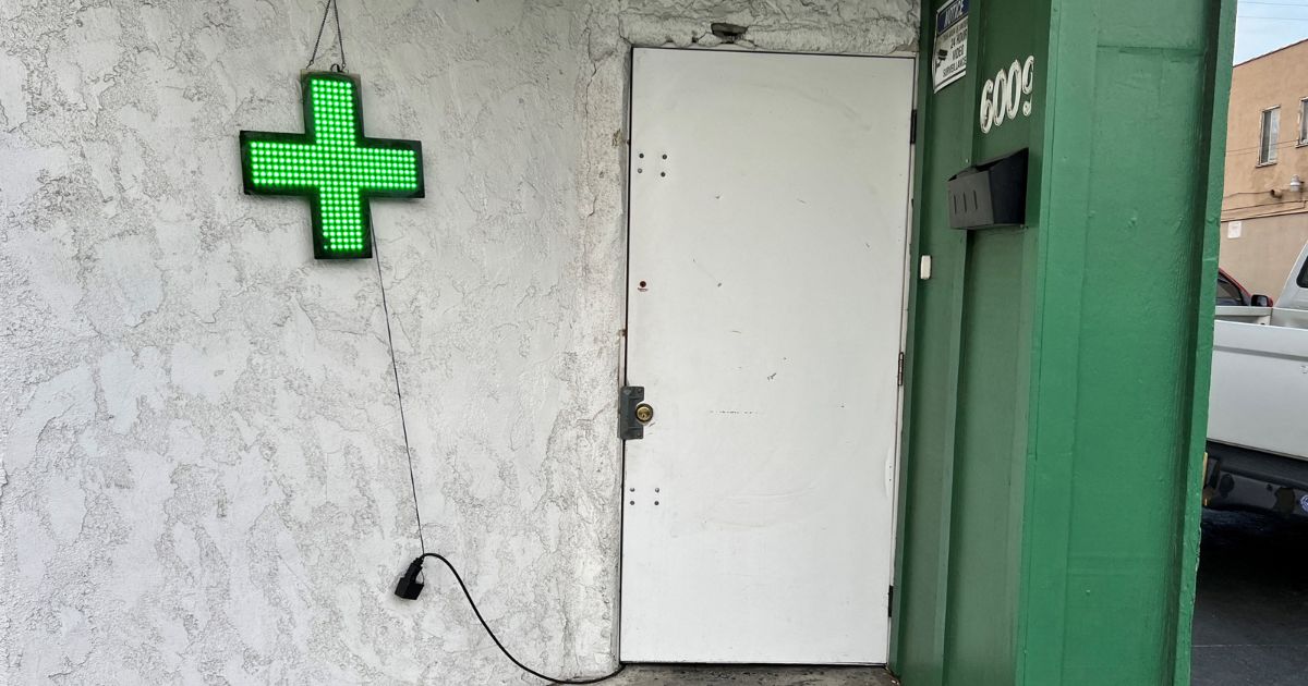 A sign with a green cross is seen outside an unlicensed cannabis dispensary in East Los Angeles, an unincorporated area in Los Angeles County, California, on December 17, 2022.