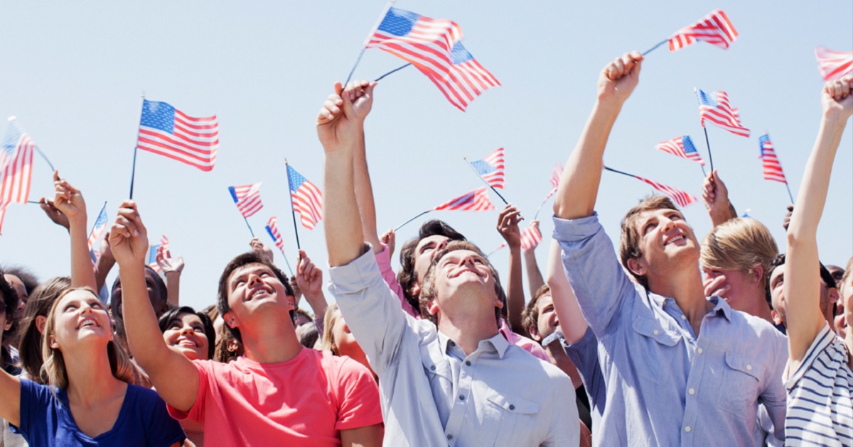Group of men and women looking up while waving American flags.