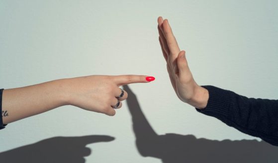 A woman points at a man's open palm in this stock image.