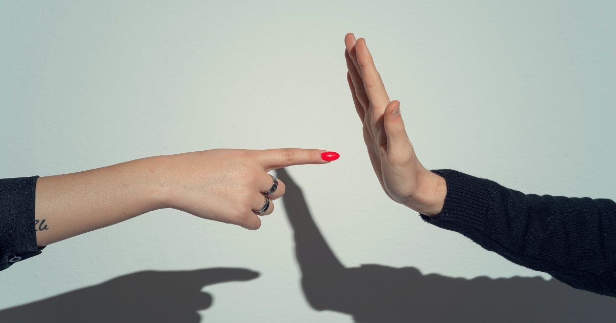 A woman points at a man's open palm in this stock image.