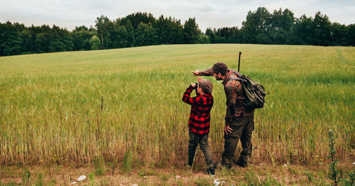 A father and son are pictured hunting for boar in an open grass area. Moments like these may come more rarely, as the Biden administration passed a new law prohibiting youth hunting and archery classes at school from receiving federal funding.