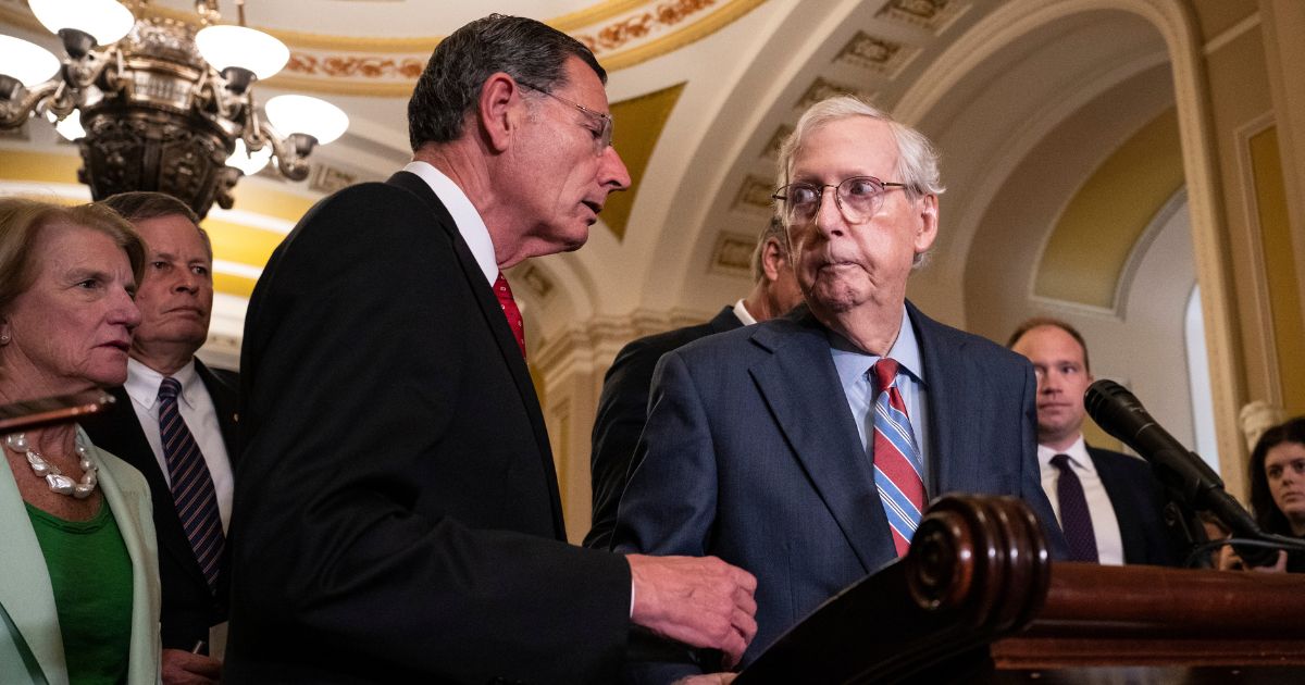 Sen. John Barrasso (R-WY) reaches out to help Senate Minority Leader Mitch McConnell (R-KY) after McConnell froze and stopped talking at the microphones during a news conference after a lunch meeting with Senate Republicans U.S. Capitol on Wednesday in Washington, D.C.