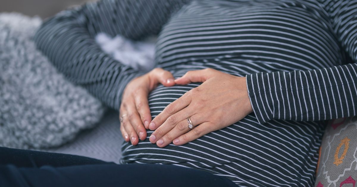 A pregnant woman holds her belly in this stock image.