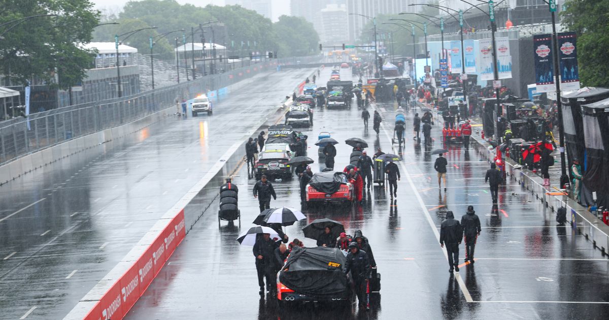 Crew members push cars off the course after a weather-shortened NASCAR Xfinity Series The Loop 121 at the Chicago Street Course on July 2, 2023 in Chicago.