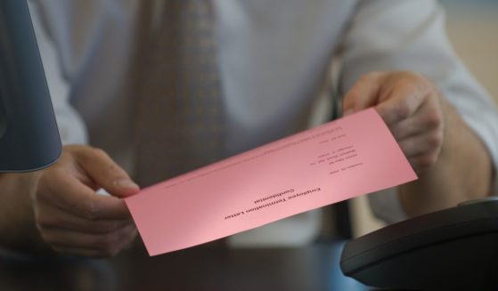 The above stock image is of a man holding a pink slip.