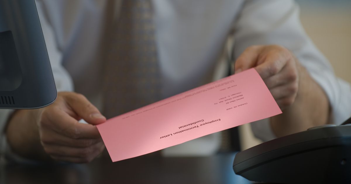 The above stock image is of a man holding a pink slip.
