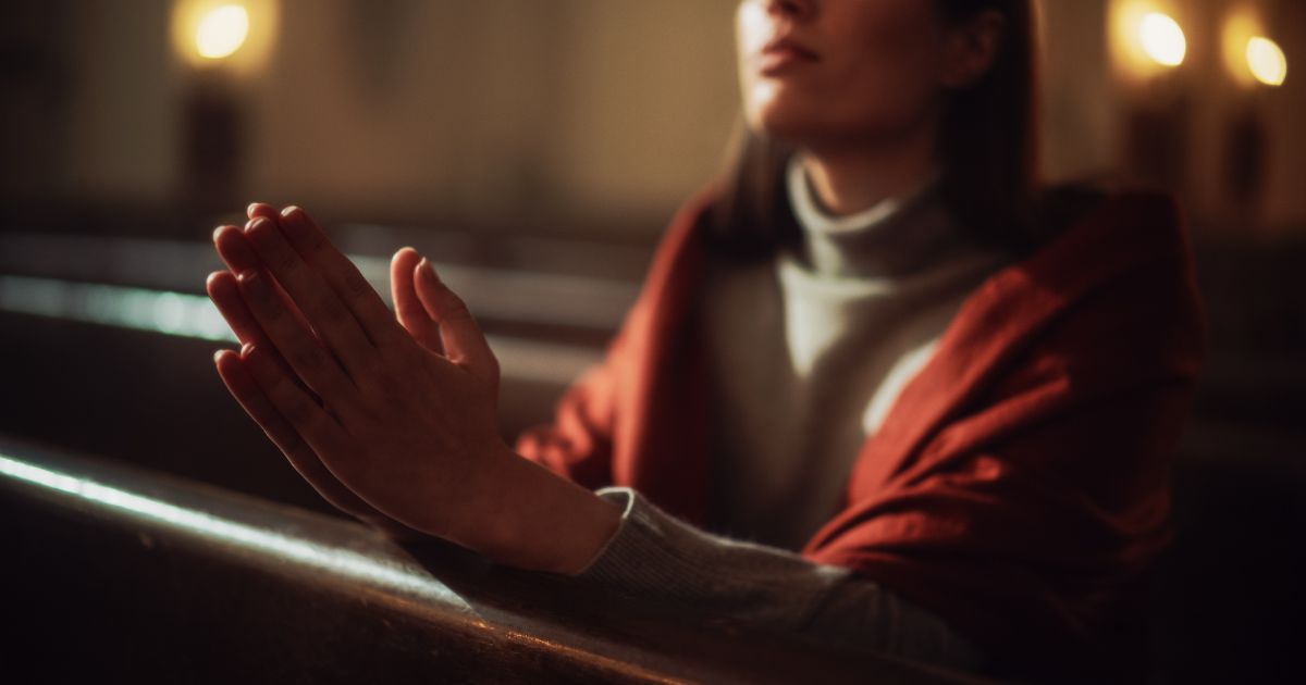 A woman prays in the above stock image.
