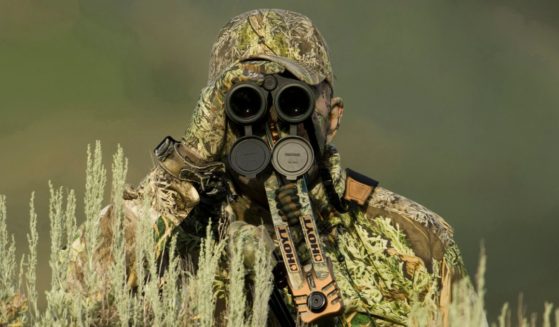 This stock image shows a hunter in camo peering through binoculars.