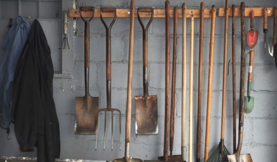 This stock image depicts a wall of gardening tools, including a pitchfork.