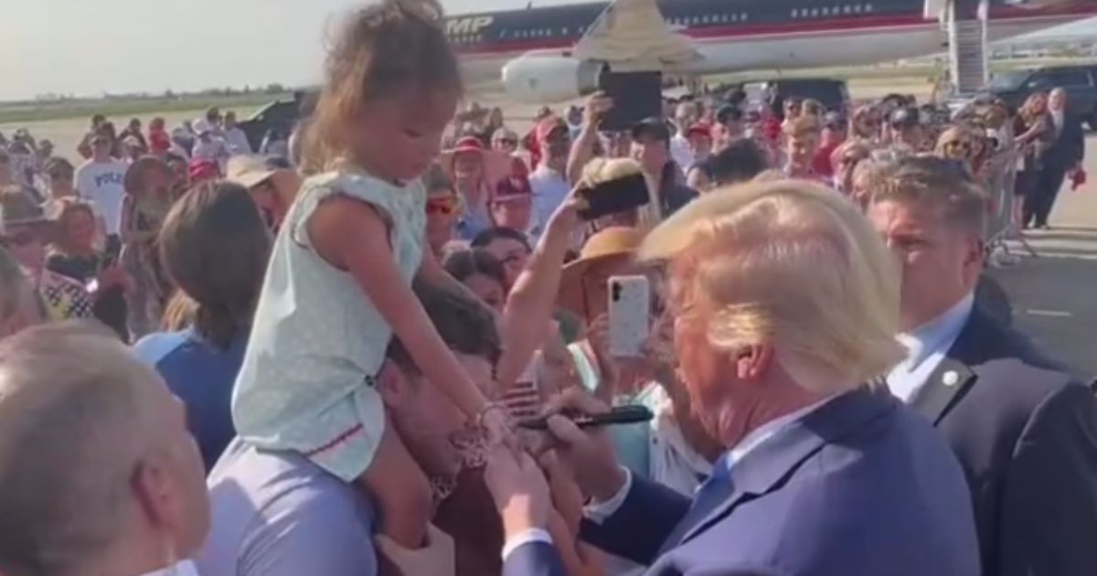 Former President Donald Trump signs a young girl's hand in Louisiana.
