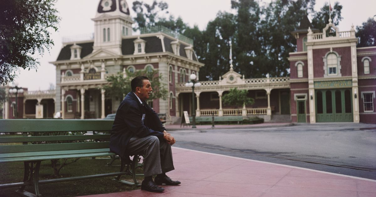 Portrait of American movie producer, artist, and animator Walt Disney (1901 - 1966) as he sits on a bench in his Disneyland amusement park, Anaheim, California, 1950s.