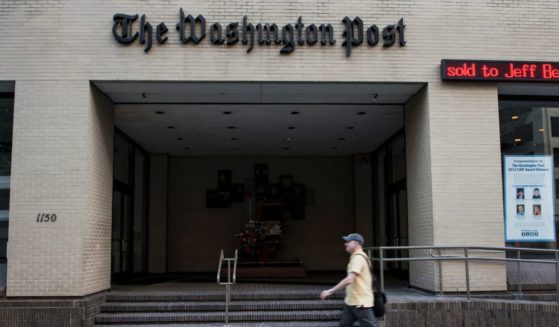 A man walks past The Washington Post building on August 5, 2013 in Washington, DC, after it was announced that Amazon.com founder and CEO Jeff Bezos had agreed to purchase the Post for USD 250 million.