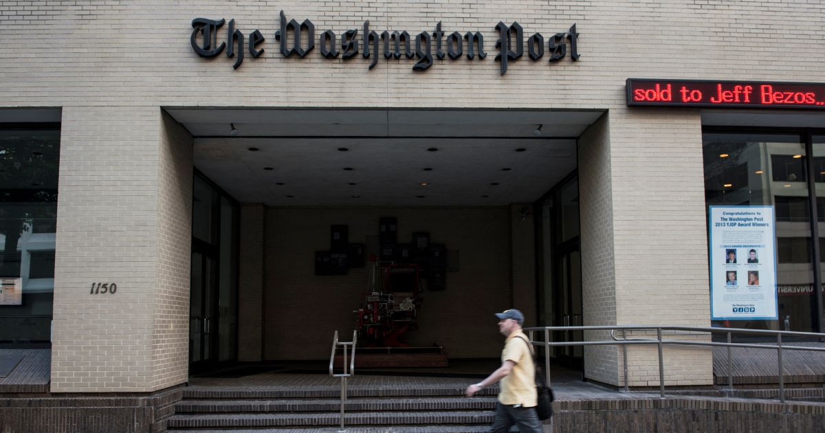 A man walks past The Washington Post building on August 5, 2013 in Washington, DC, after it was announced that Amazon.com founder and CEO Jeff Bezos had agreed to purchase the Post for USD 250 million.