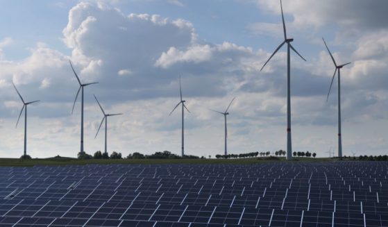Wind turbines spin behind a solar energy park on June 2, 2022, near Prenzlau, Germany.