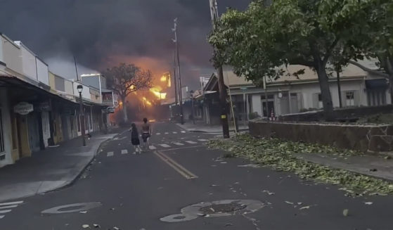 People walk the streets of Lahaina town, Hawaii, on Wednesday as wildfires engulf multiple structures, forcing residents to evacuate.