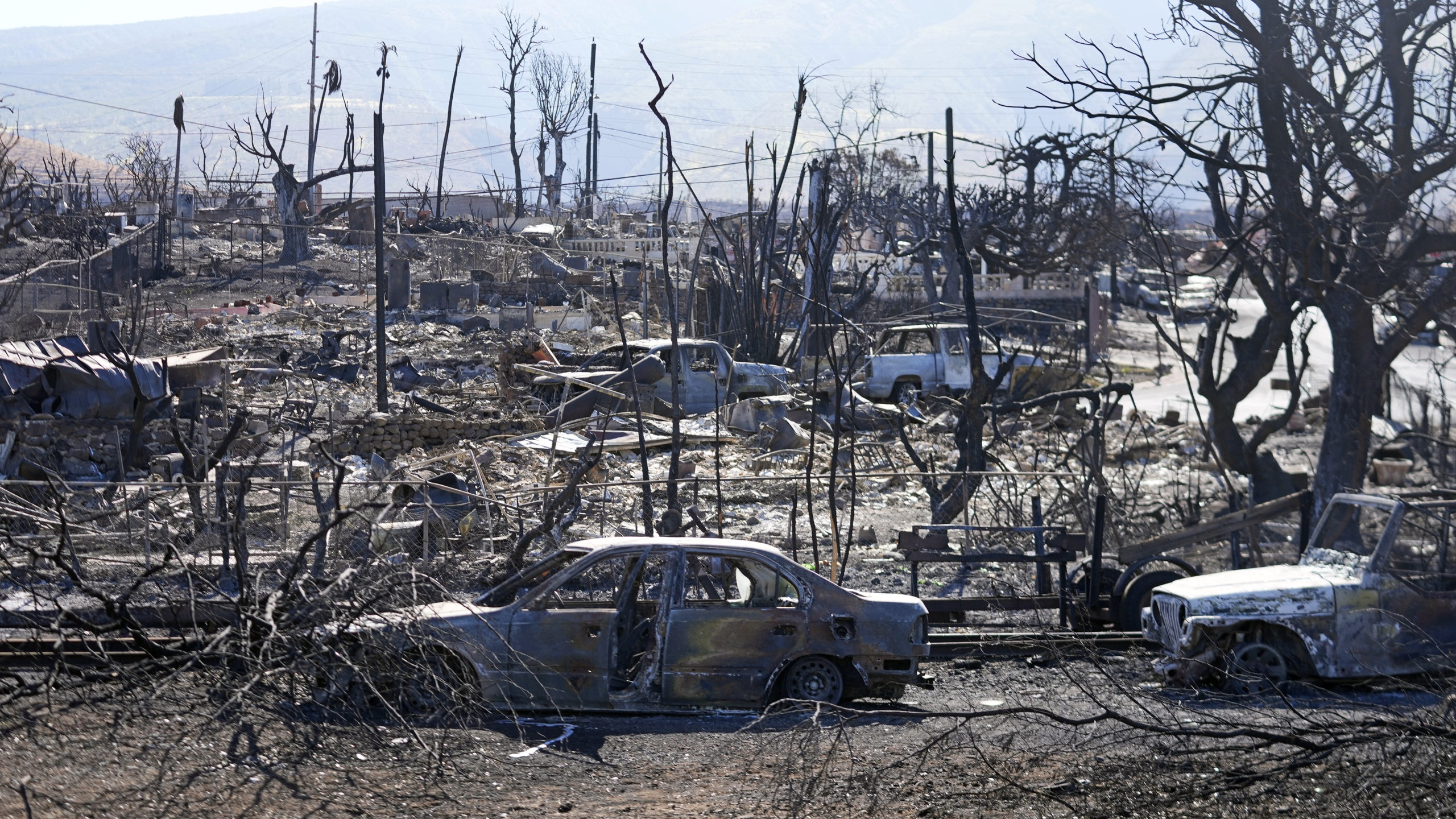 Homes and cars destroyed by a devastating fire are seen Sunday in Lahaina, Hawaii.