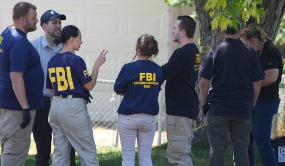 FBI officials and other law enforcement officers stand outside the home of Craig Robertson after he was shot and killed by FBI agents in a raid on his home in Provo, Utah, on Wednesday morning.