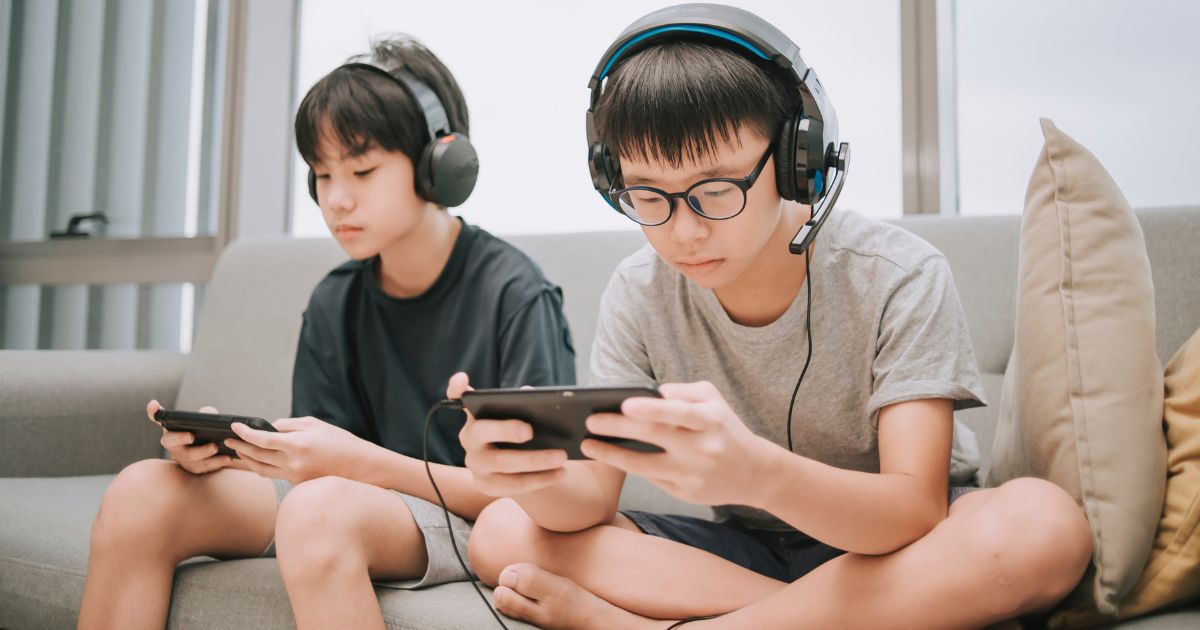 Two boys are pictured playing video games on their cell phones. A new lawsuit is alleging one company is targeting children who play their games with "illegal gambling."