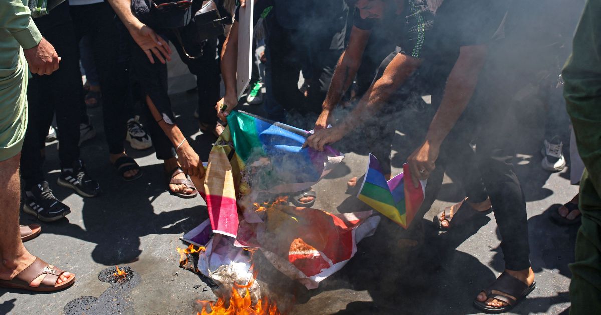 Supporters of Iraq's Sadrist movement burn posters depicting the LGBT flag during a protest in Basra on June 30.