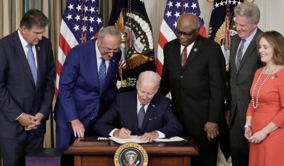 Sen. Joe Manchin, left, stands next to fellow Democratic senators as President Joe Biden signs The Inflation Reduction Act in the White House on Aug. 16, 2022.