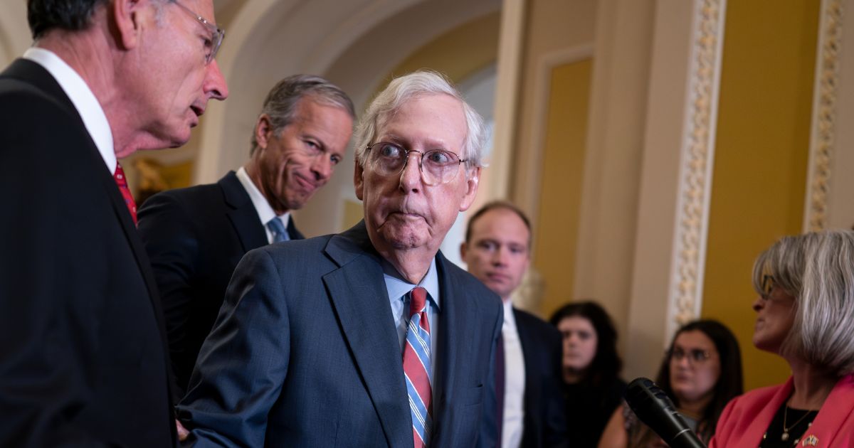 Mitch McConnell being helped by other senators after freezing at the podium